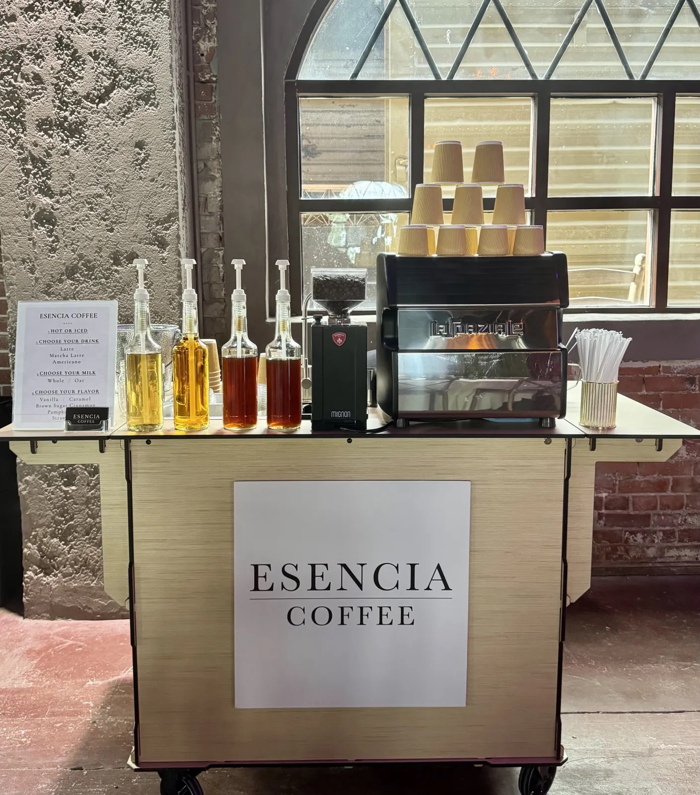 The Esencia Coffee mobile coffee cart with its menu sign and house syrups, set up for a wedding
