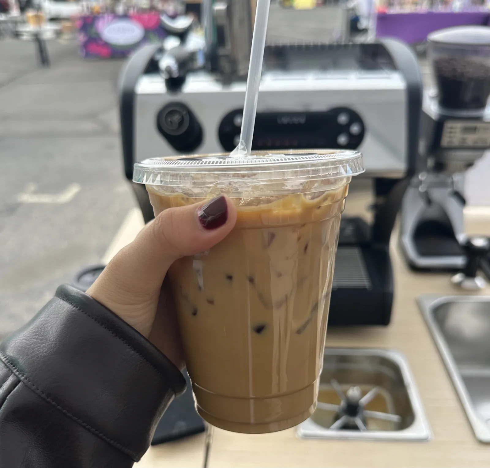 Event coffee catering: an iced latte from the Esencia Coffee cart held up in front of the espresso machine at an outdoor event
